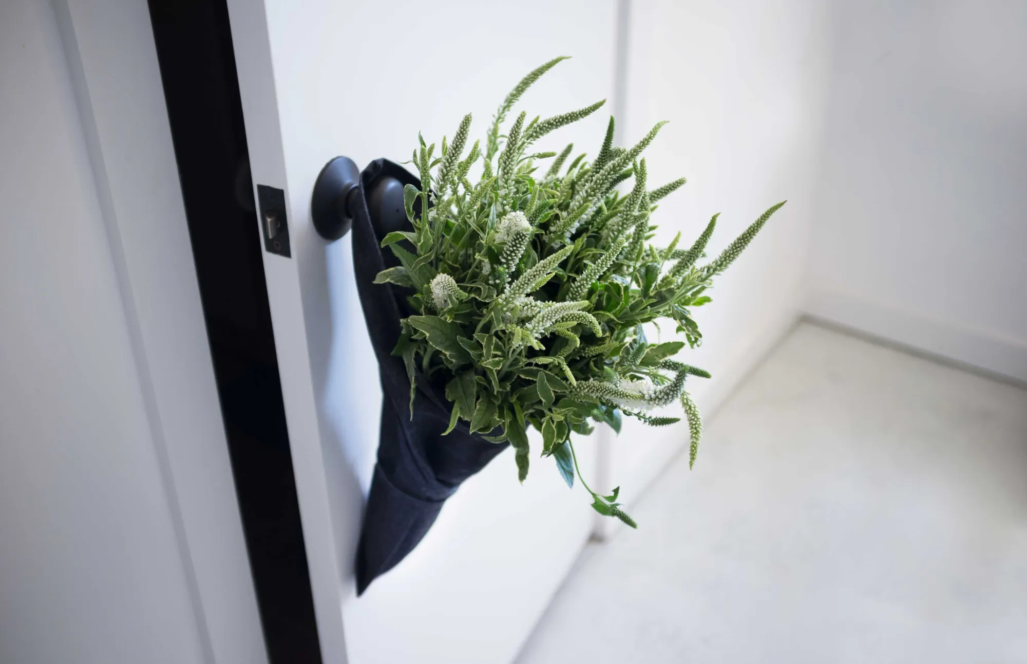 Aplat Jardin tote hanging on a door handle with fresh greens